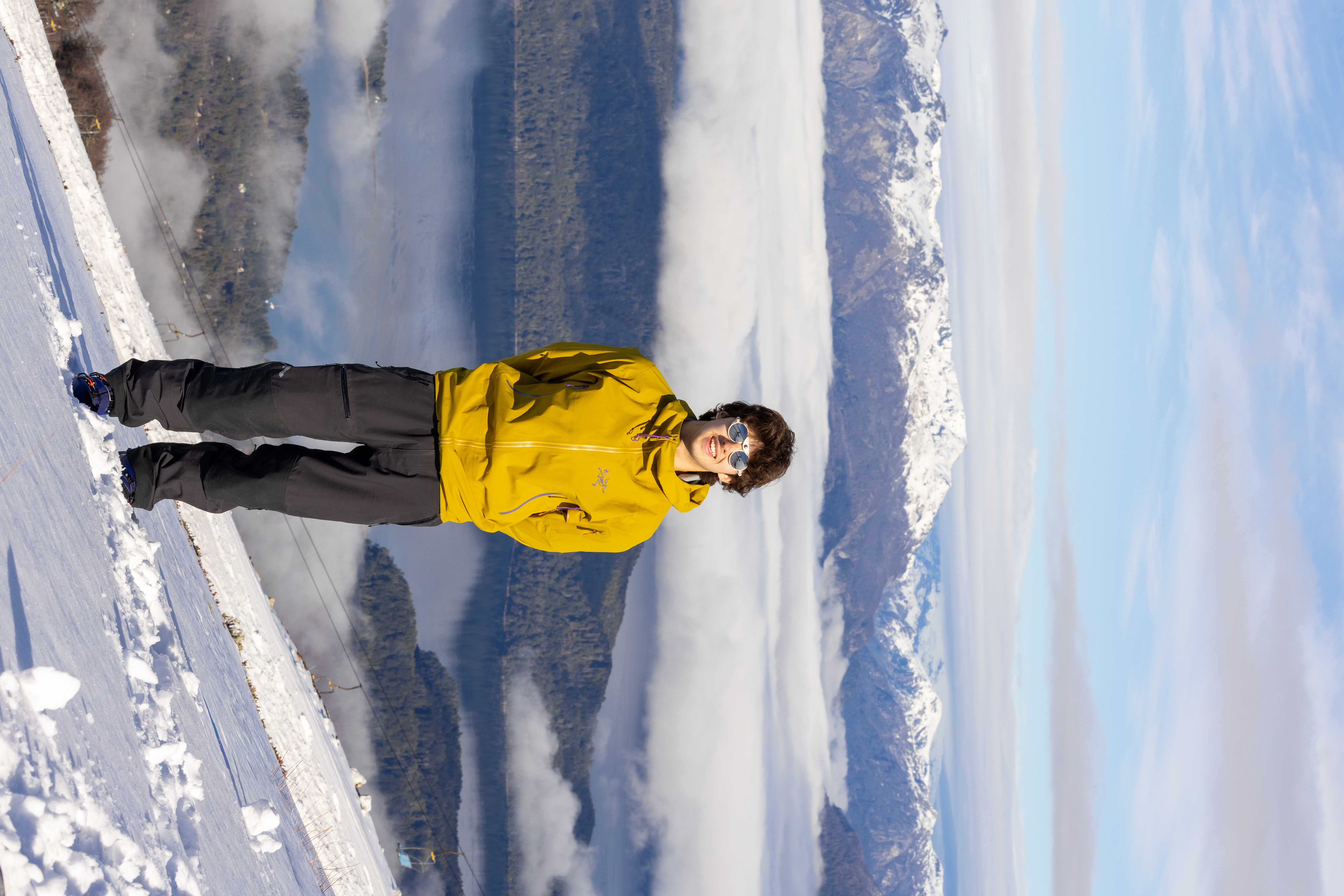 Oliver Gray smiling on a ski slope with a mountain range in the background